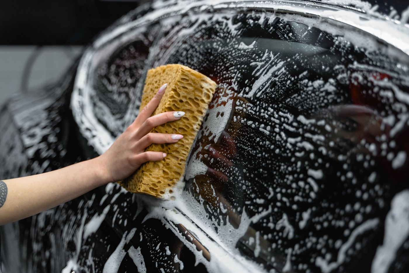Person vacuuming crumbs from a car seat with a crevice tool